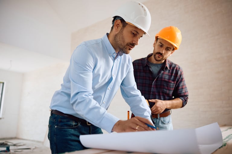 Architect and worker reviewing plans at construction site
