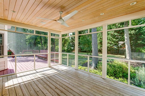 Screened-in porch with ceiling fan and view of green backyard
