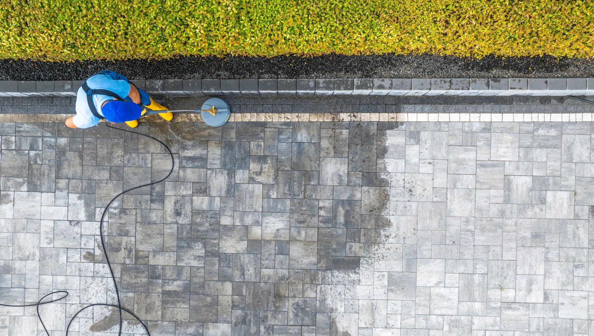 Worker pressure washing stone patio pavers