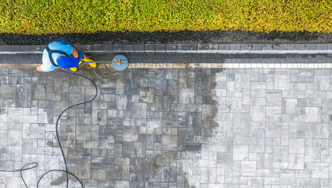 Worker pressure washing stone patio pavers
