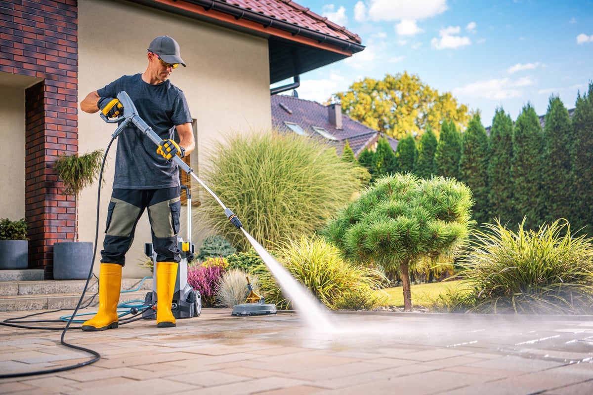 Power washing a patio surrounded by greenery