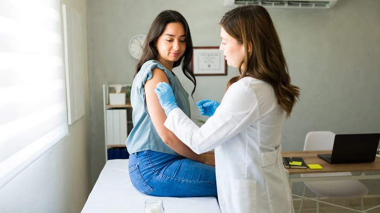 A medical professional wearing gloves giving an injection into a patient's upper arm