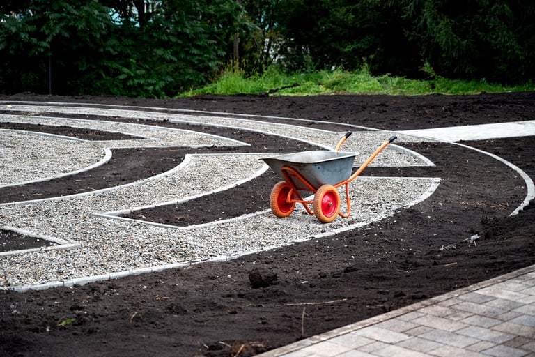 Wheelbarrow on a landscaped garden pathway with gravel and soil sections
