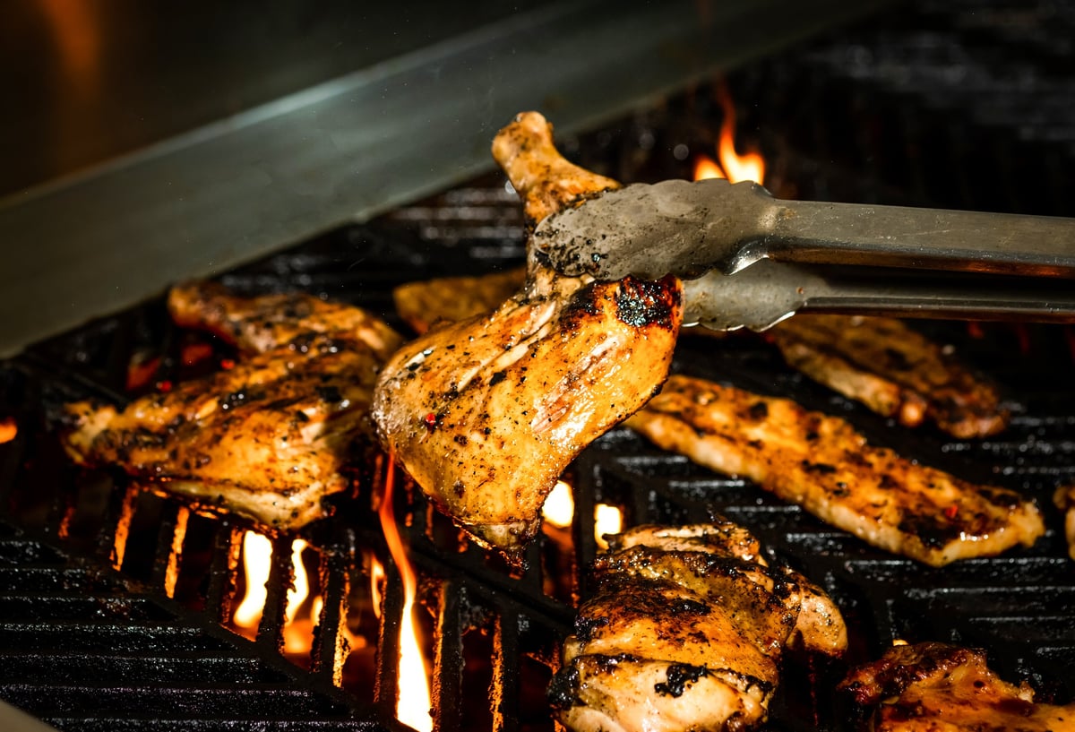Sizzling mixed grill with chicken and flames on a hot grill closeup