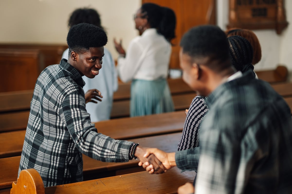 Two men warmly shaking hands at church showing unity and friendship