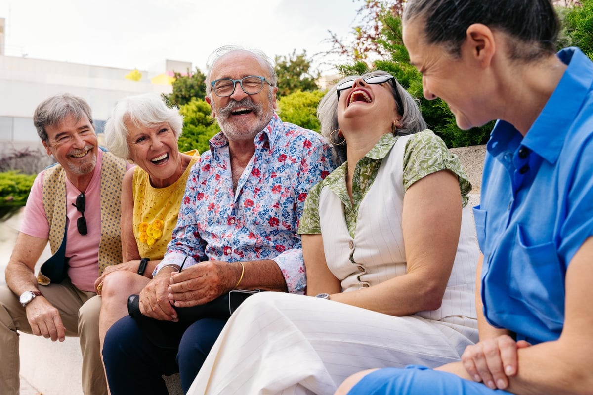 Grupo de amigos mayores riendo y compartiendo al aire libre