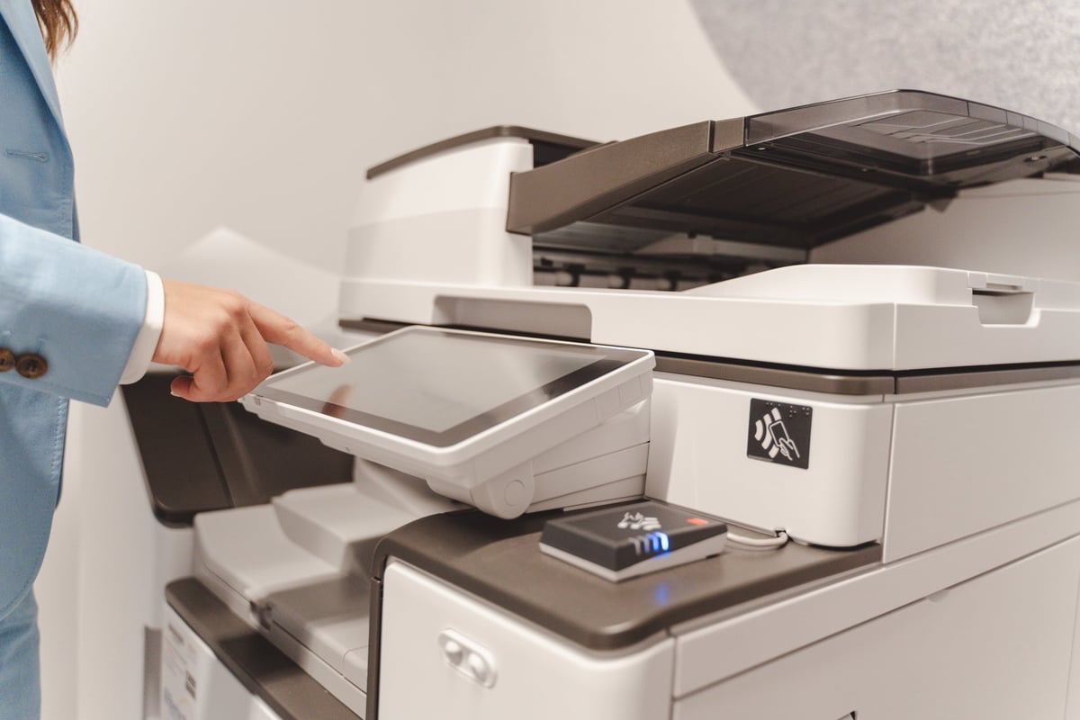 Office worker using touchscreen of a modern professional multifunction printer