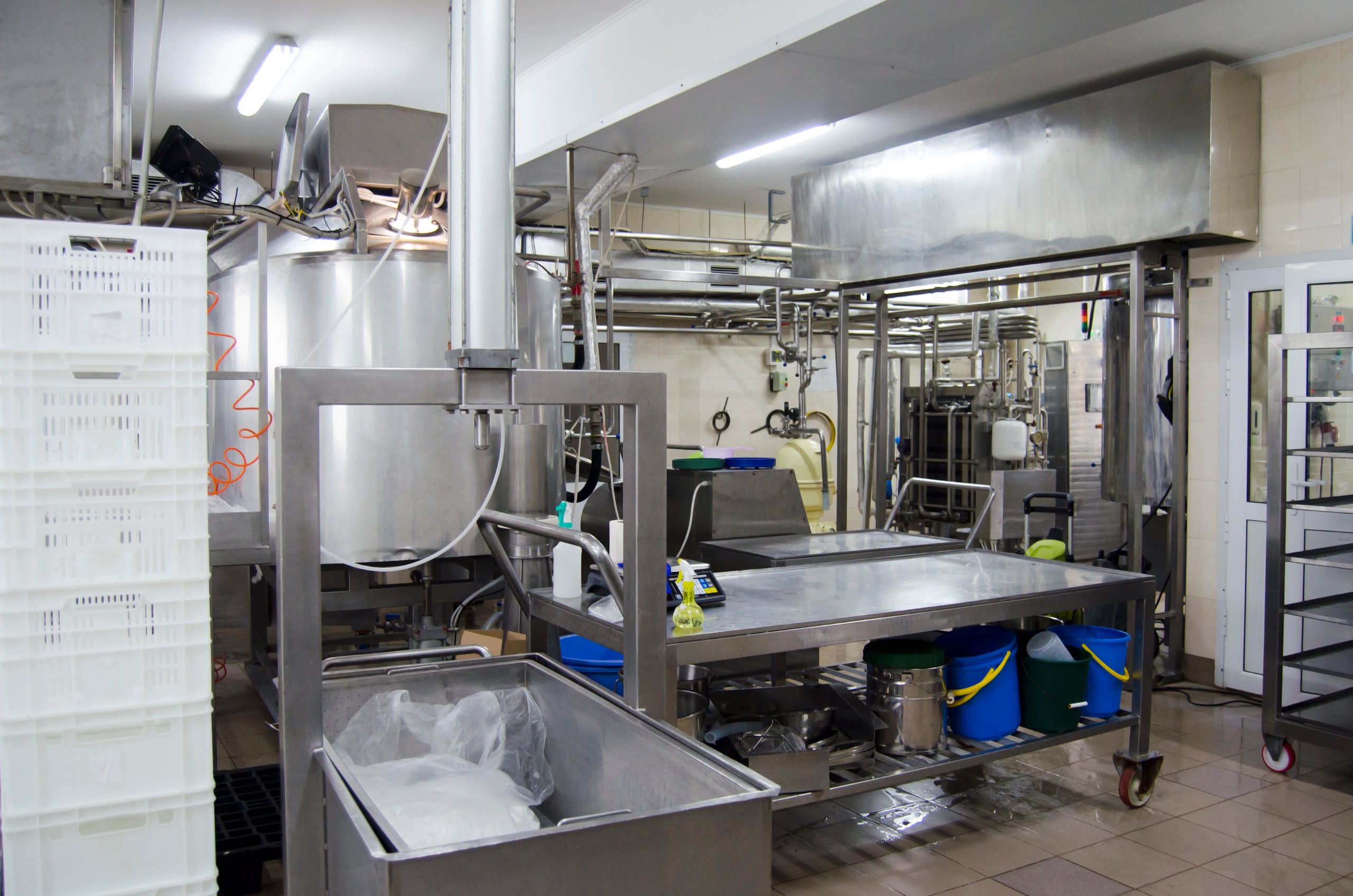 Stainless steel food processing machinery and pipework inside an industrial dairy production facility