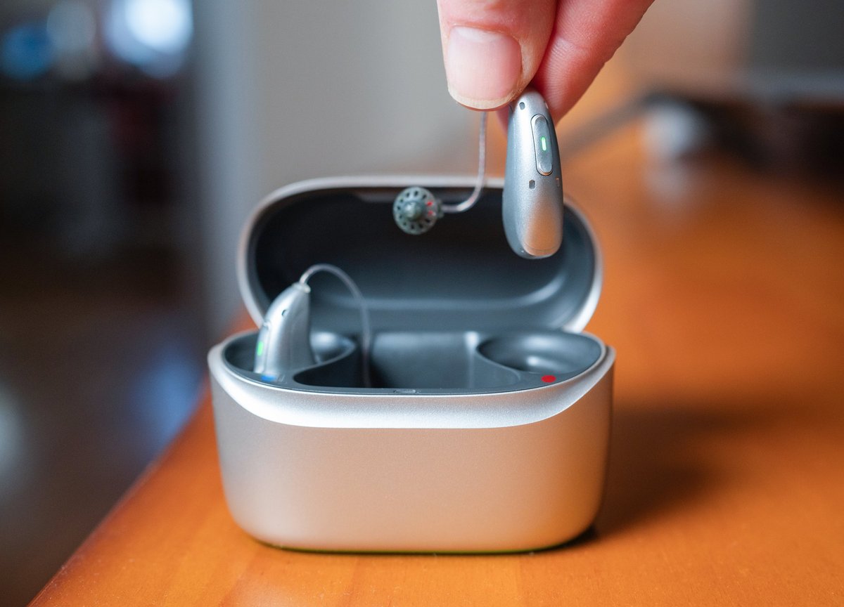 Rechargeable hearing aid held over its charging case