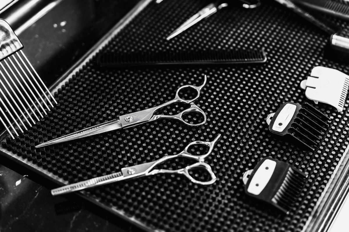 Scissors, combs, and hair clipper attachments on dark surface
