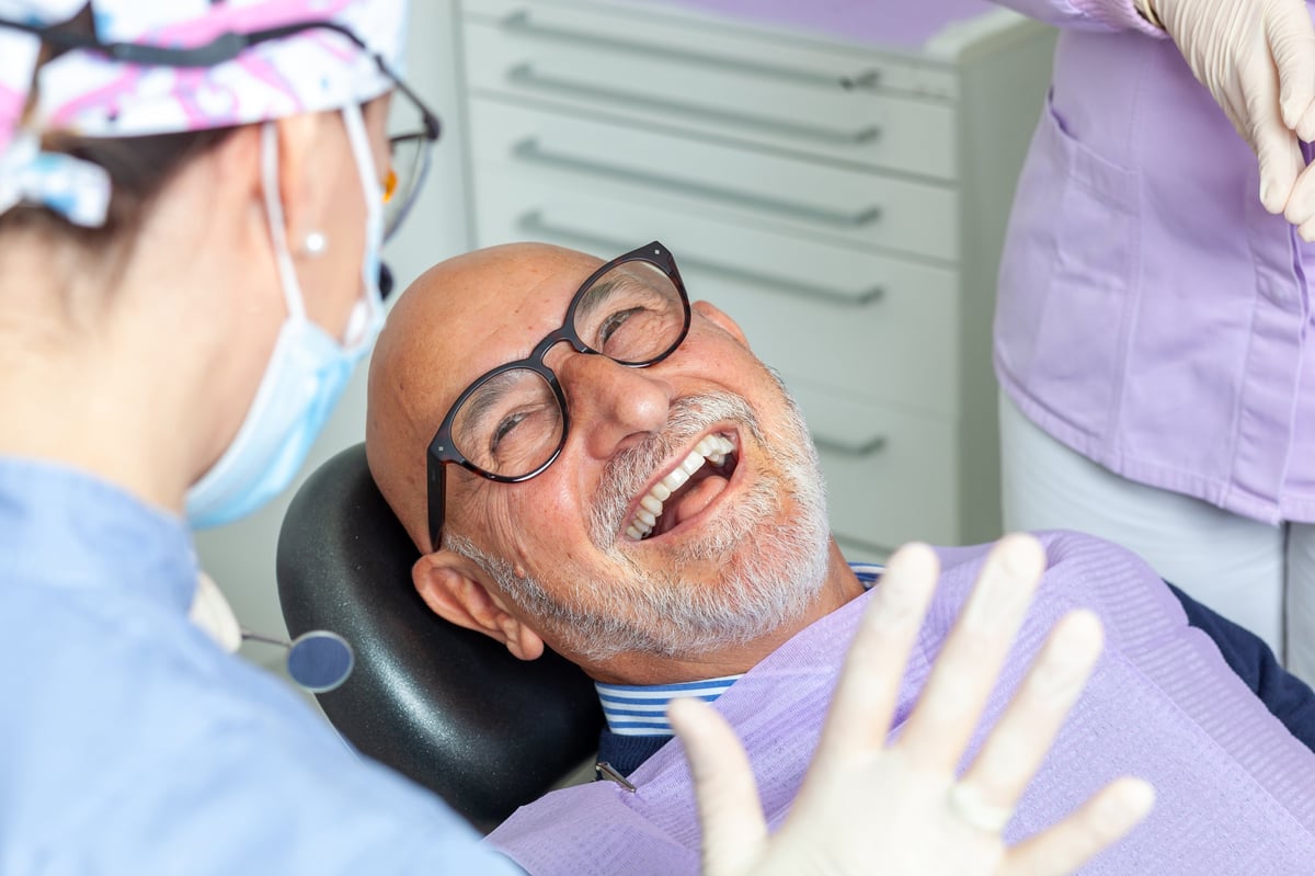 Happy senior man laughing with a dentist after a same-day dental fix