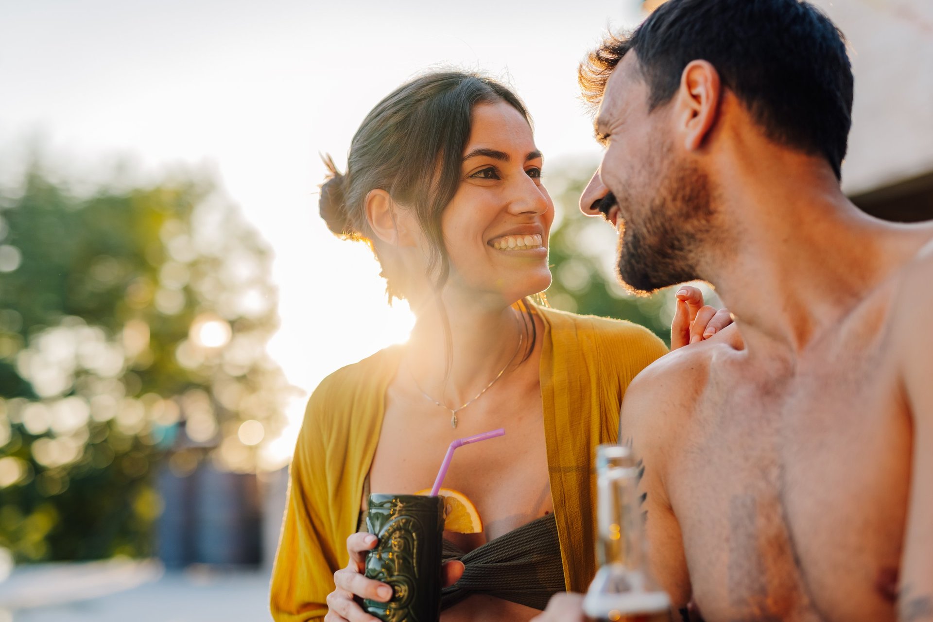 Couple drinking cocktails by pool at sunset