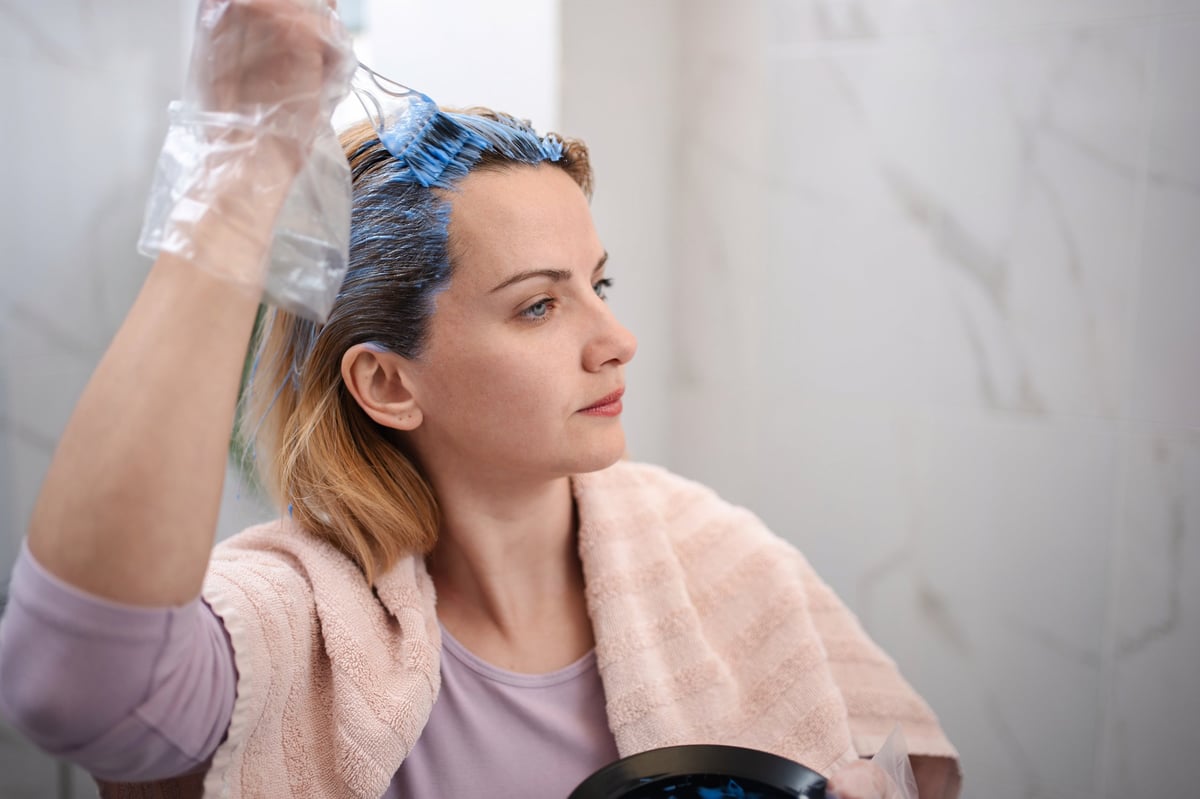 Woman applying blue dye on blonde hair