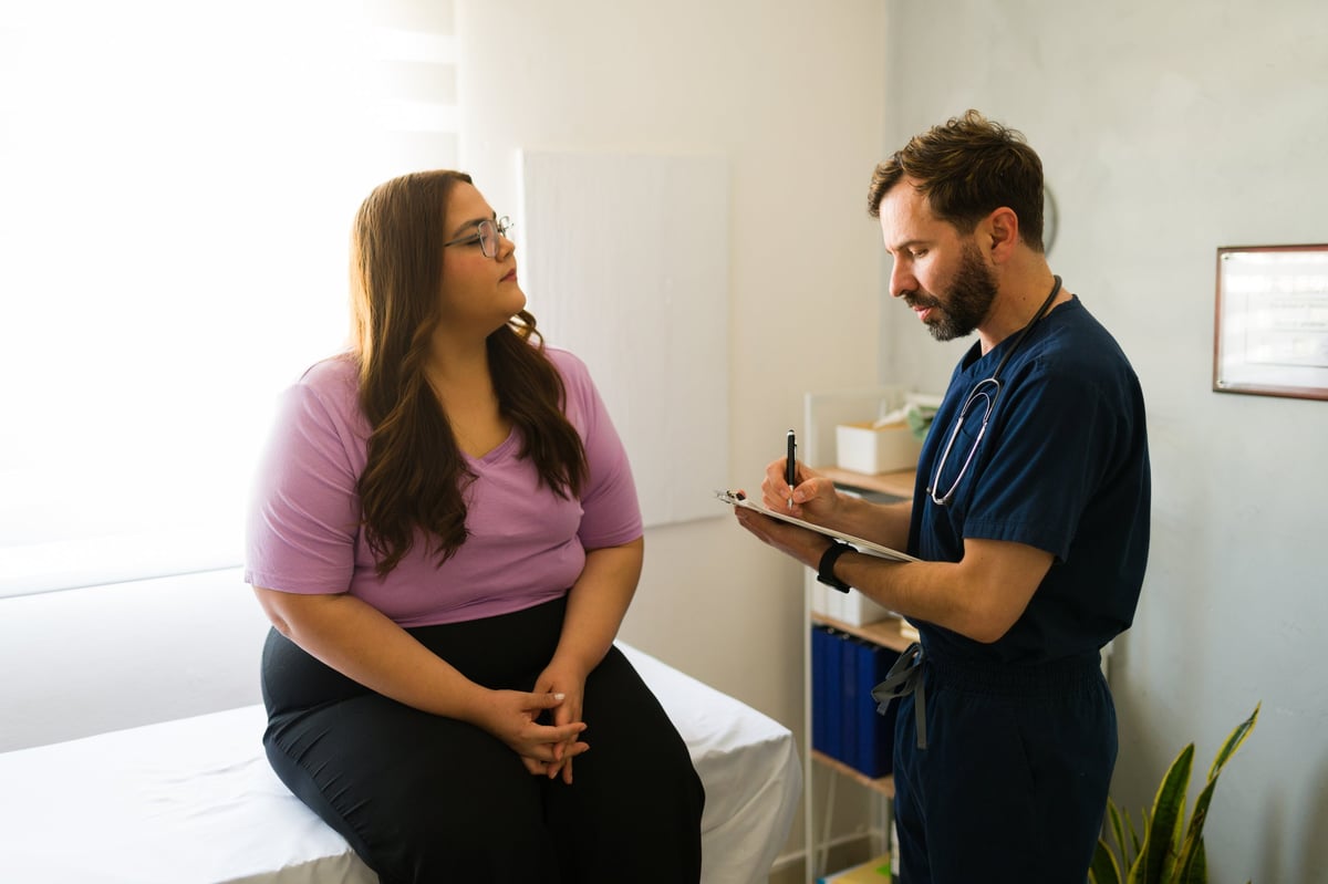 El doctor conversando con una paciente en consulta, escuchando atentamente, luz natural cálida — fotografía editorial premium