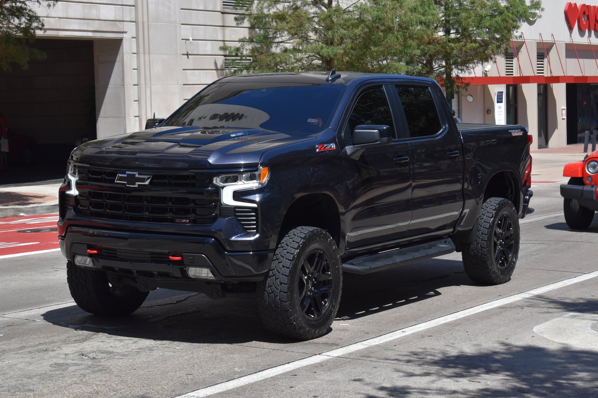 A black pickup truck used for business driving through a city financial district