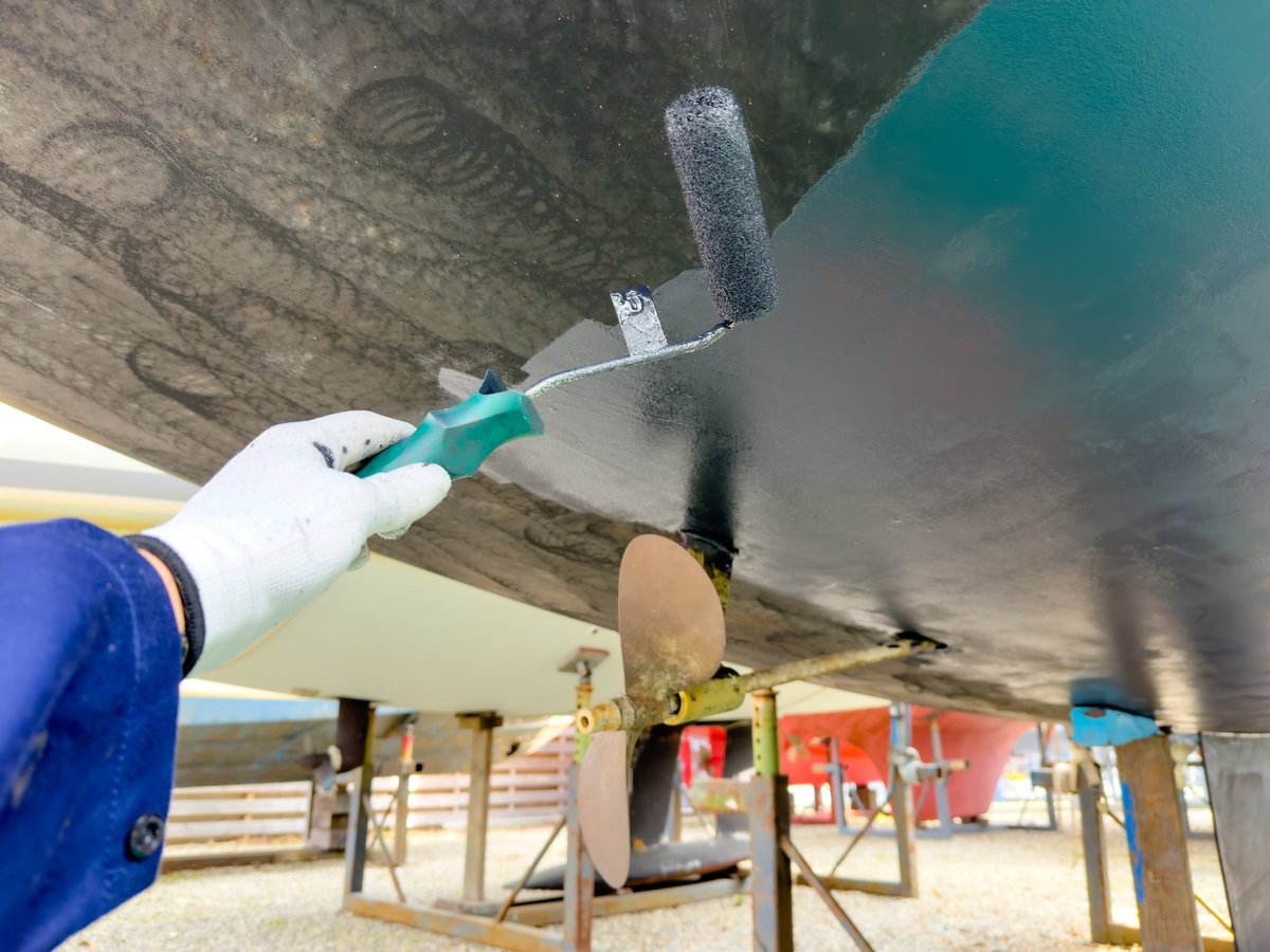 Sailing boat on stilts being painted in boatyard