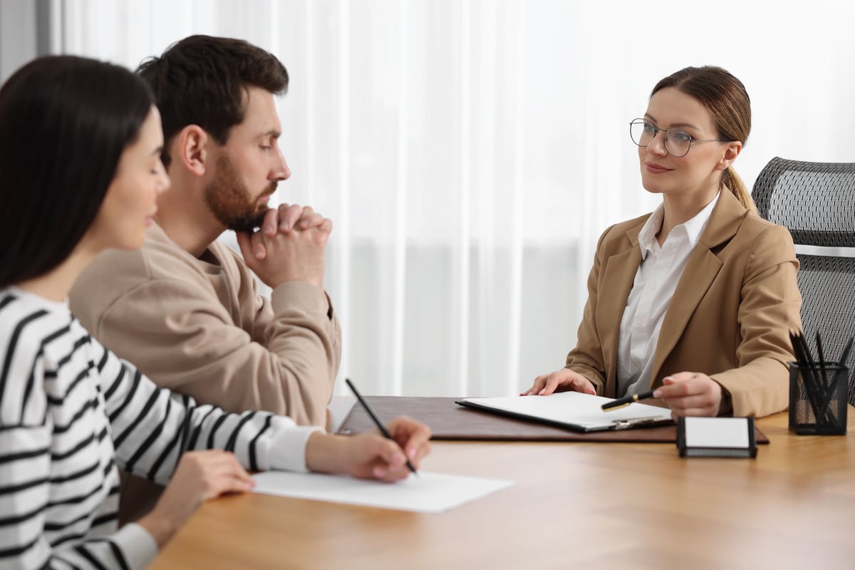 Couple signing documents with notary professional in office