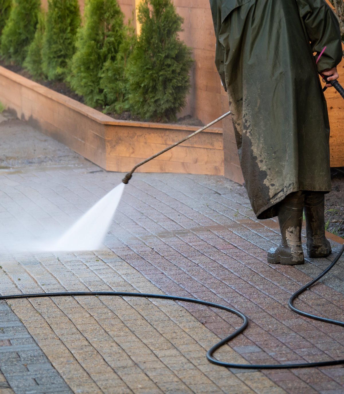 Professional pressure washing a paved driveway to remove stains and restore clean surface