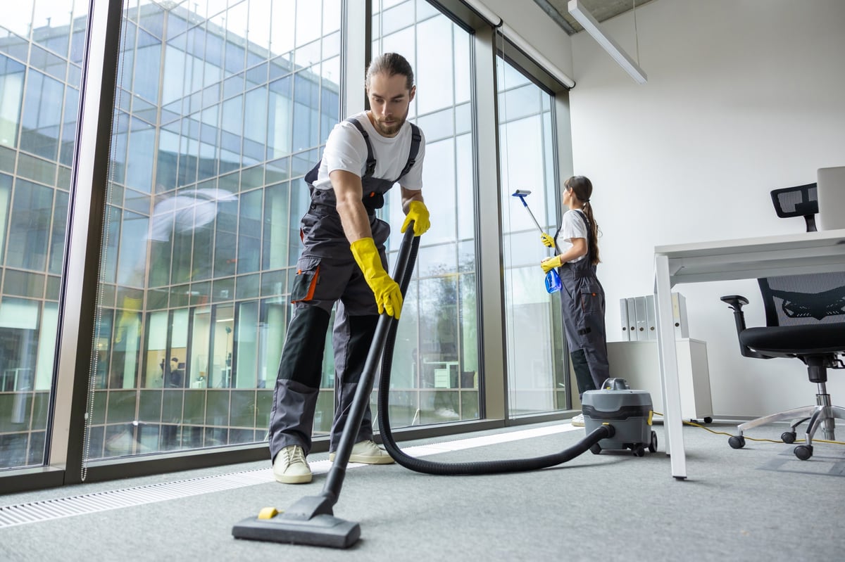Professional cleaner vacuuming the floor in a conference room after hours