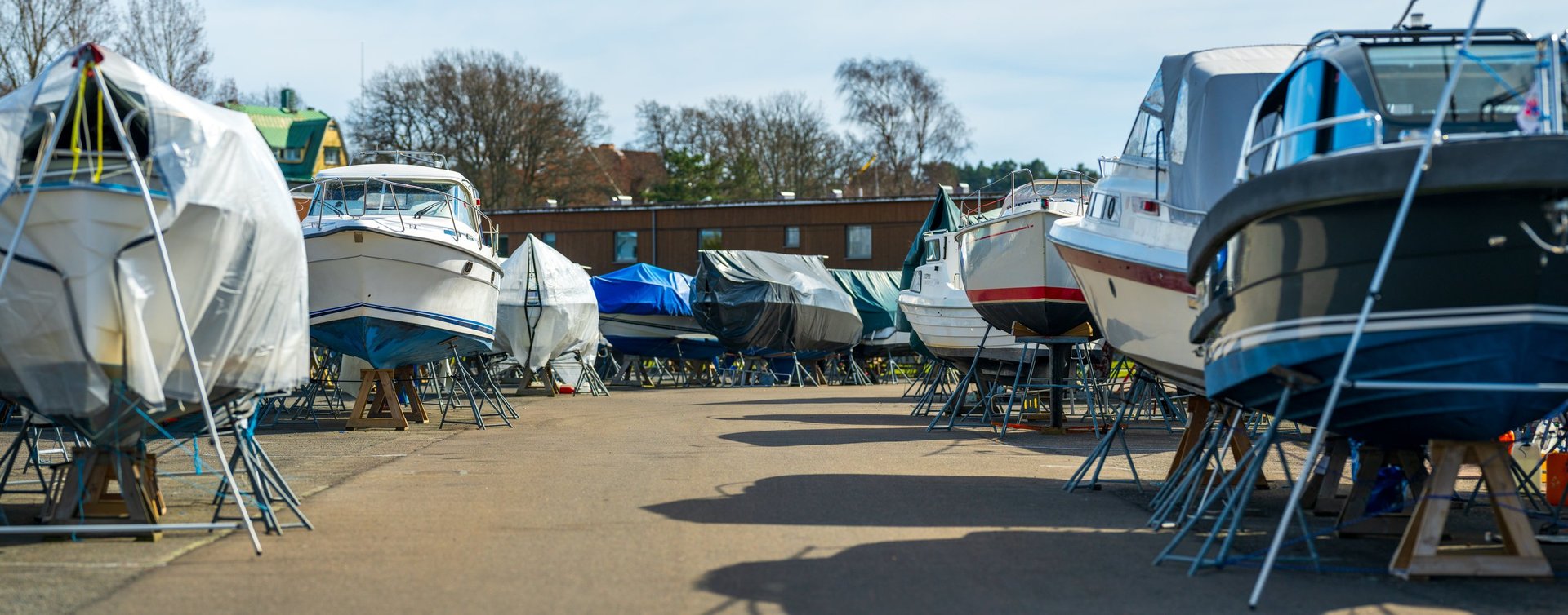 Covered motorboats lined up at boatyard after professional cleaning
