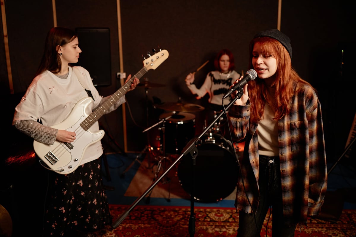 Girl singing into microphone with rock band on stage