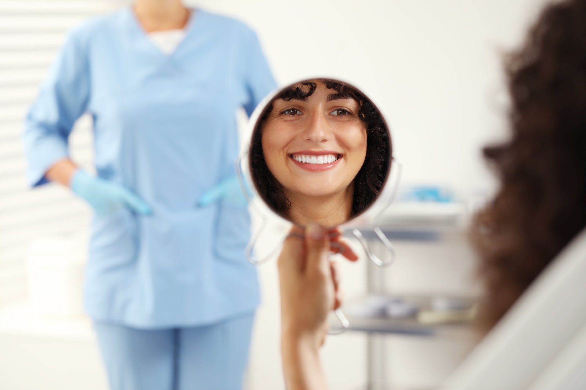 Patient admiring her new porcelain veneers in a mirror during a cosmetic dentistry appointment