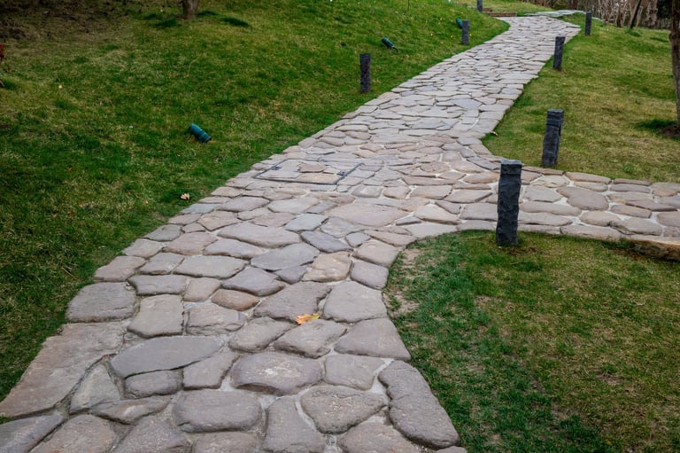 Natural stone walkway winding through green lawn with landscape lighting
