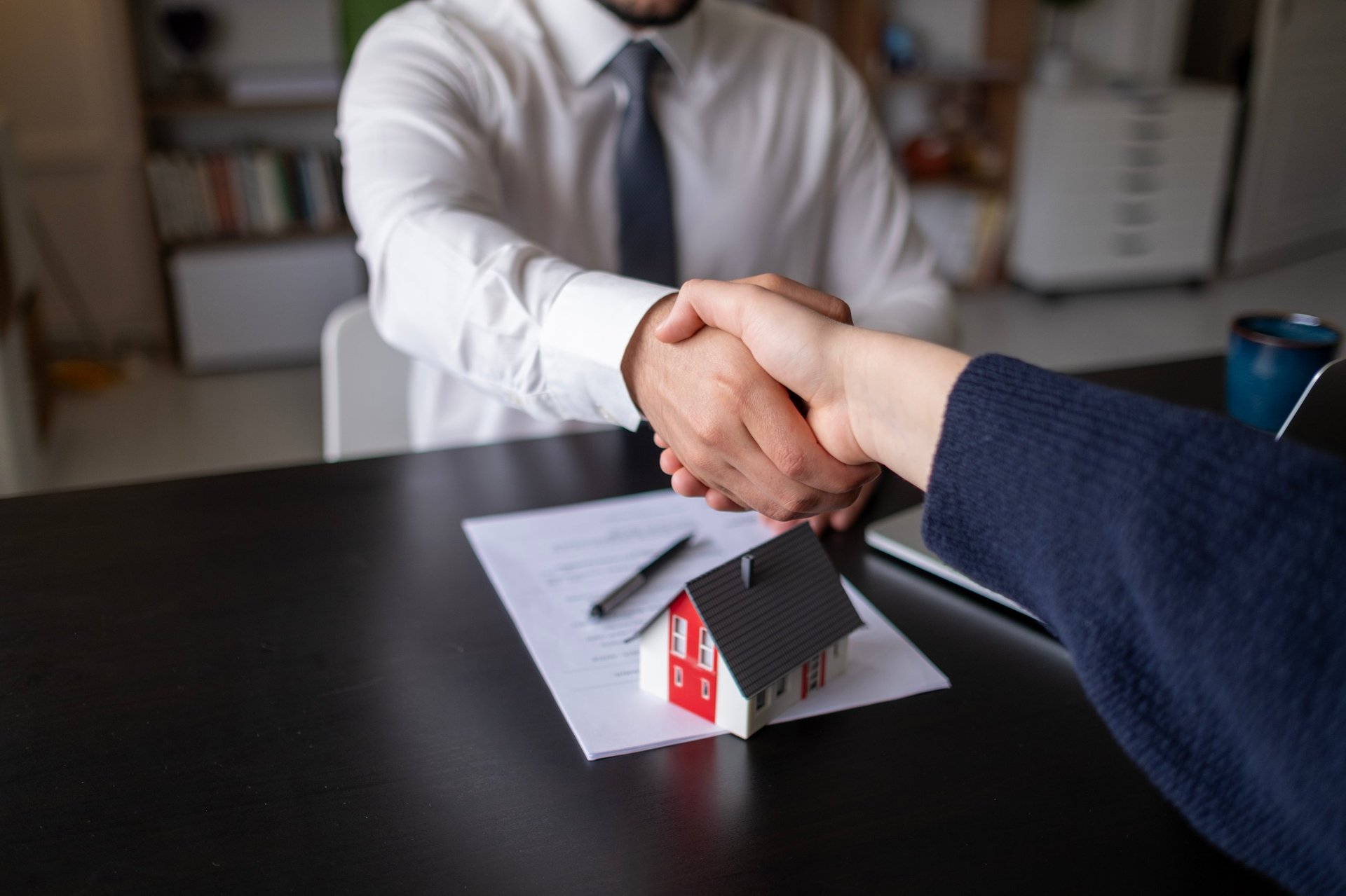 Agentes inmobiliarios cerrando un acuerdo de venta con un apretón de manos