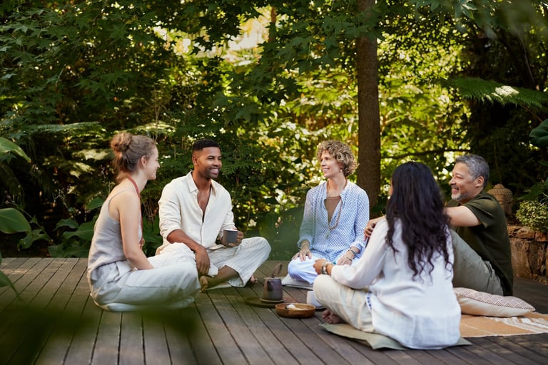 Diverse group relaxing together outdoors at a peaceful wellness retreat, enjoying tea and conversation in nature