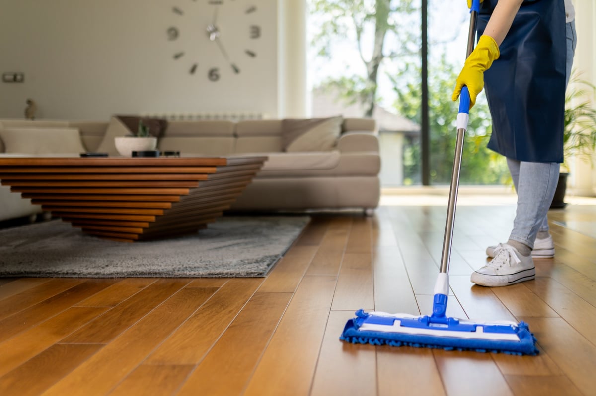 A person mopping hardwood floors in a bright, stylish living room