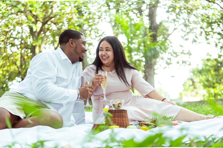 Couple toasting with champagne glasses at a romantic luxury picnic in a park