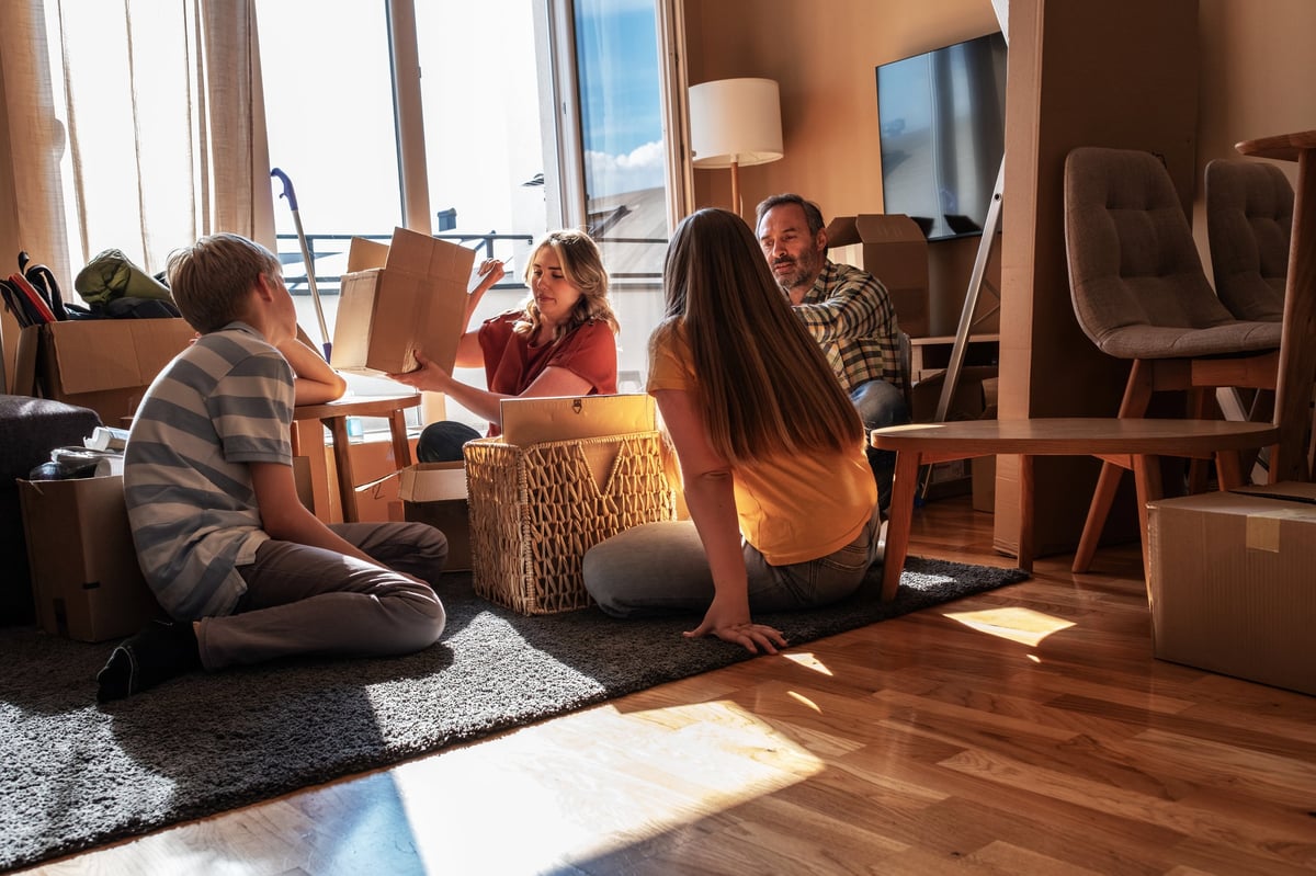 Familie packt gemeinsam Umzugskartons in der neuen 3-4-Zimmer-Wohnung aus