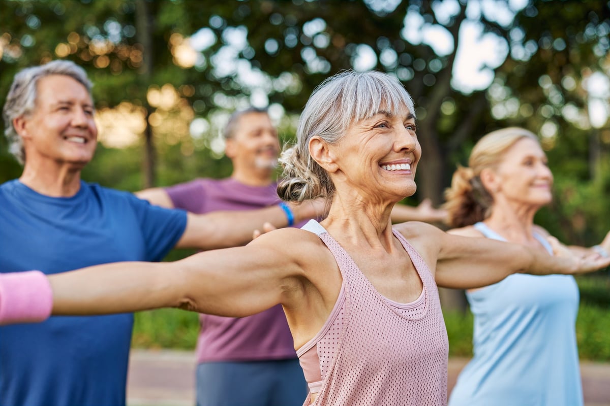 Adultos mayores haciendo yoga y estiramientos en grupo al aire libre
