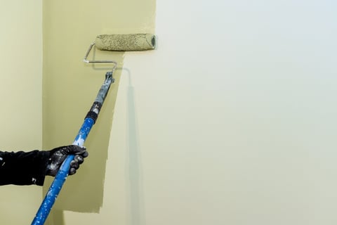 Professional painter applying paint to interior wall with roller — interior house painting serving Frisco Allen and DFW