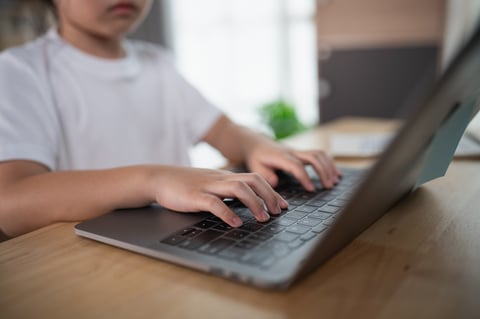 Child typing on laptop at home focusing on keyboard skills