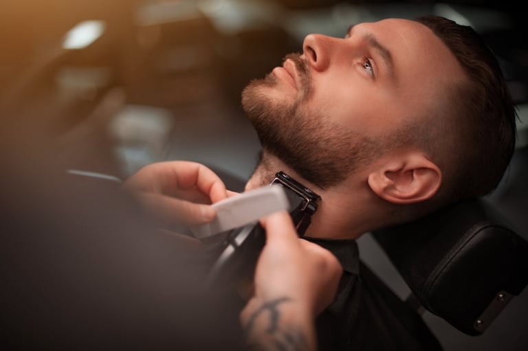 Close-up of a man receiving a precise neck and beard trim with electric clippers at a modern barbershop