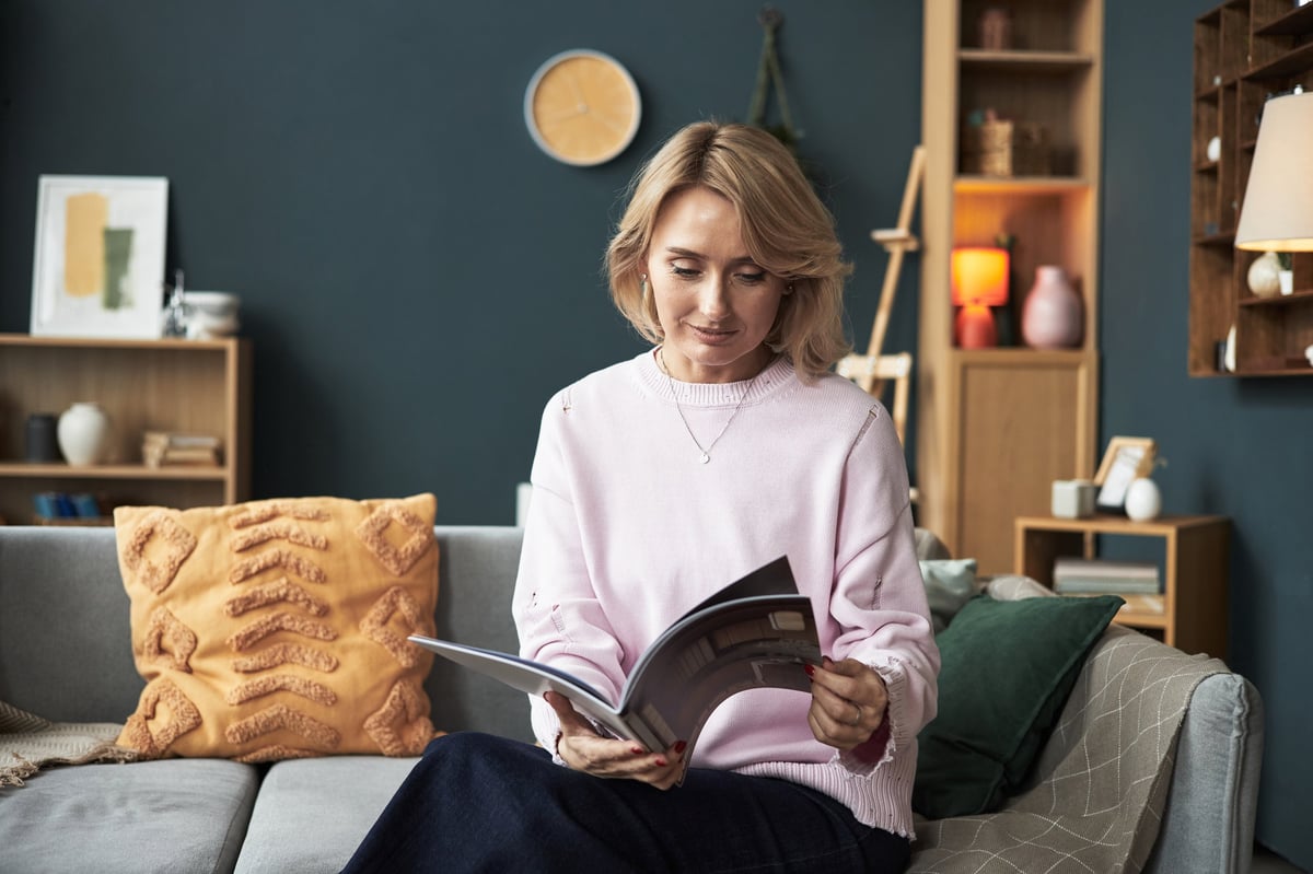 Woman reading magazine on sofa in modern living room