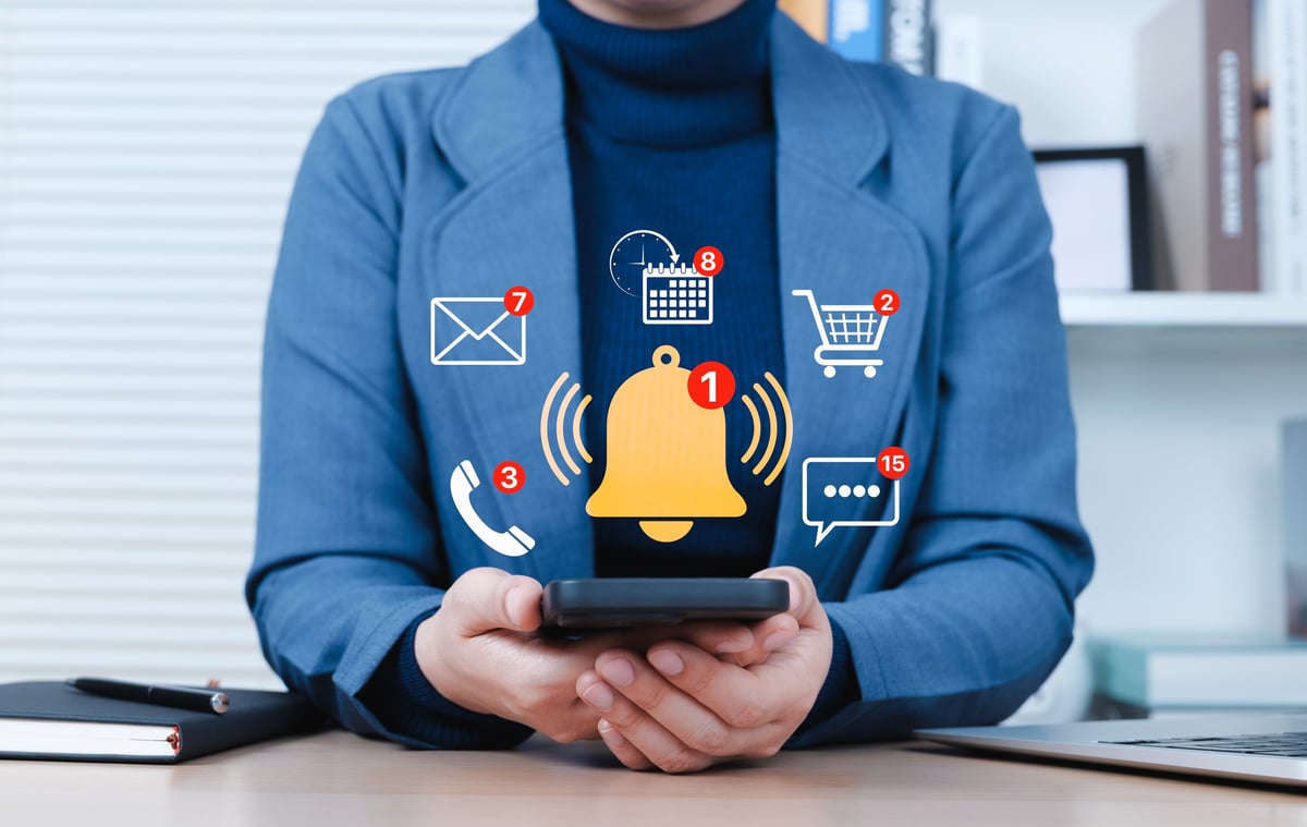 Notification Alert and Digital Communication Concept. Businessperson checks smartphone with floating multiple notification icons for messages, calls, emails, calendar events, real-time communication.