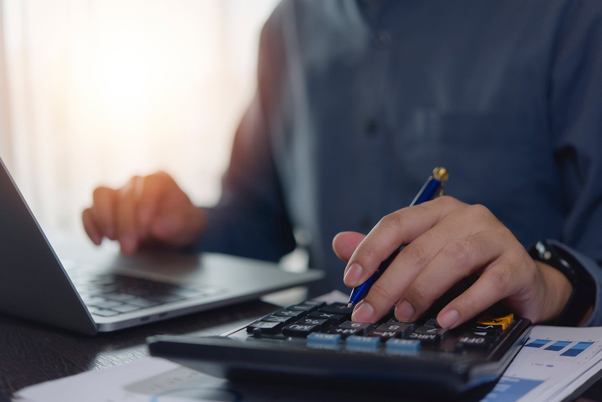 Accountant working hands using calculator and laptop, business finance planning at desk with financial tax documents