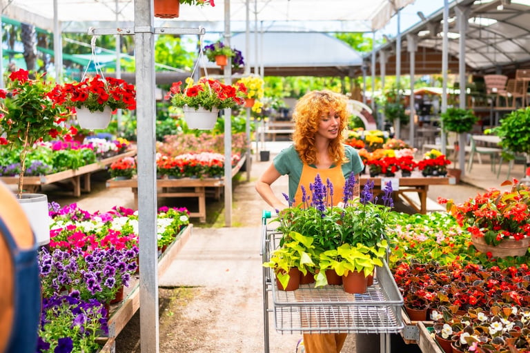 Greenhouse worker pushing a cart filled with vibrant plants