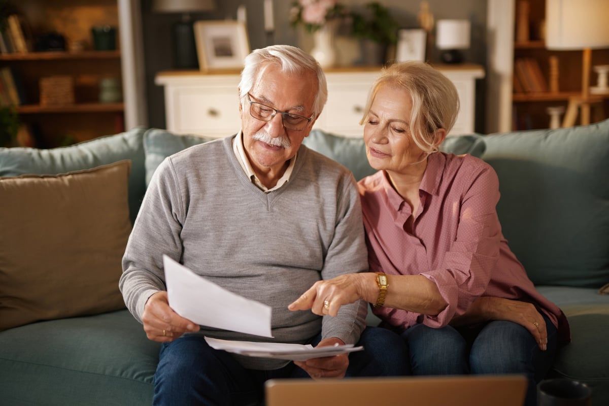 Elderly couple reviewing estate planning documents with caregiver support — geriatric care management and legal documentation for aging parents