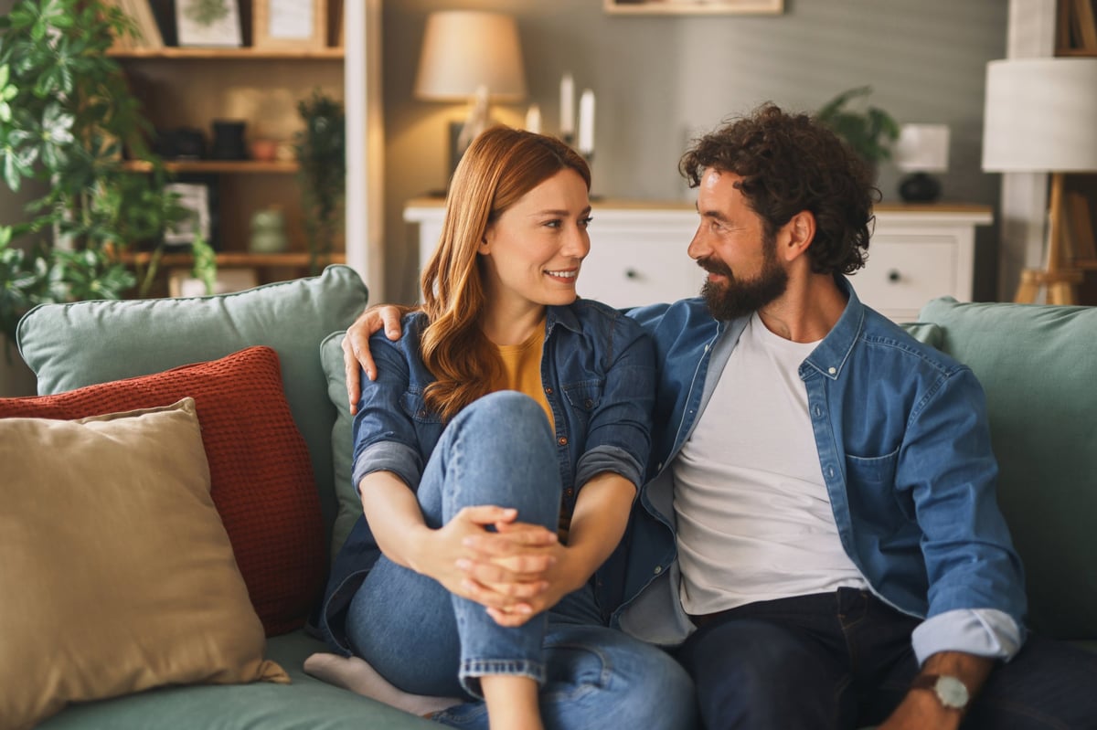 Smiling couple enjoying time together at home in genuine conversation — the quiet moment of deciding on the next chapter