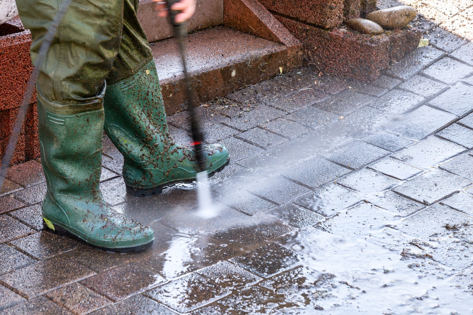 Professional patio cleaning with pressure washer on stone surface