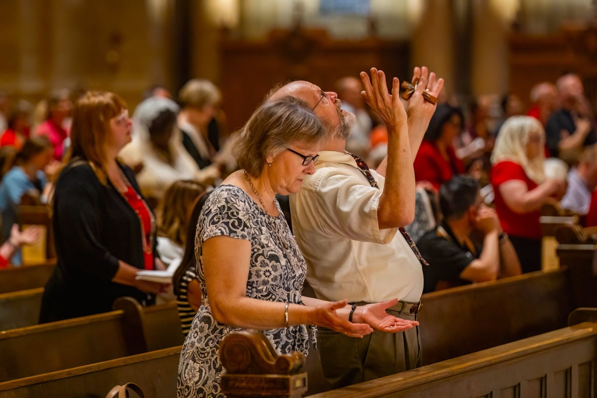 People engaged in prayer and singing within a magnificent church interior