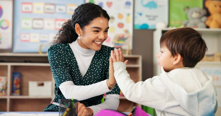 A teacher shares a celebratory high five with a smiling student in a supportive classroom