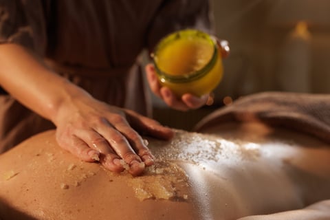 Professional hands applying luxurious body scrub treatment during spa massage session