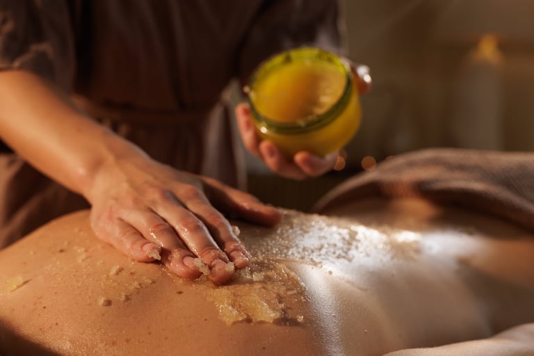 Professional hands applying luxurious body scrub treatment during spa massage session
