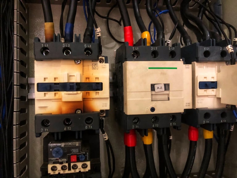 Close-up of industrial control panel contactors and wiring showing heat damage — Dylco Electric commercial repair and code compliance