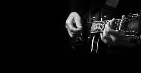 Mãos de guitarrista tocando guitarra elétrica em close-up em preto e branco