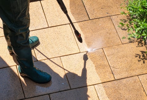 High pressure washing patio tiles showing clear before and after effect
